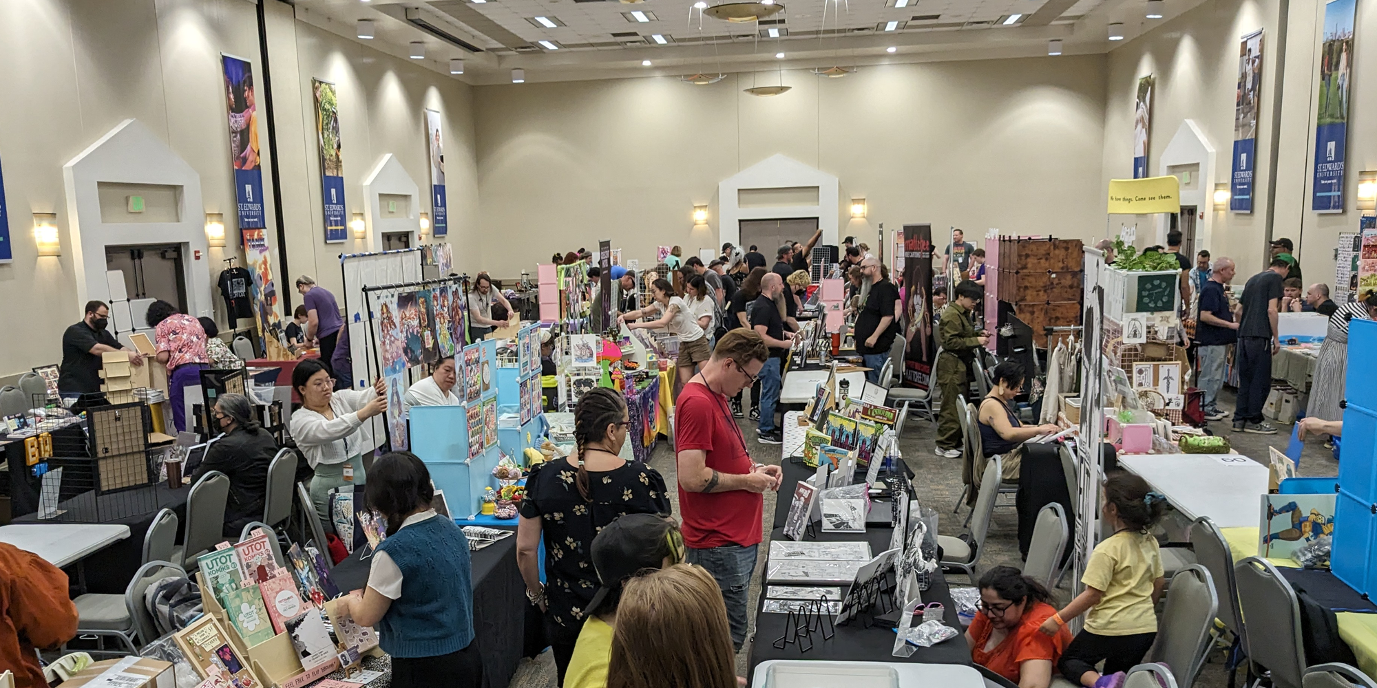 A picture of the show floor before the event's opening. The space has high ceilings and all of the vendors are busy setting up their tables.